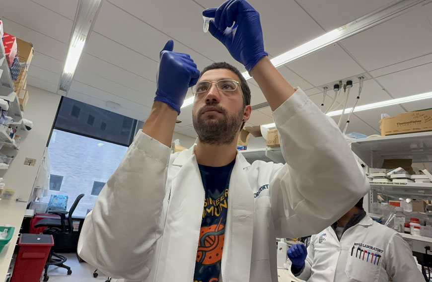 researcher looking at test tube wearing purple gloves